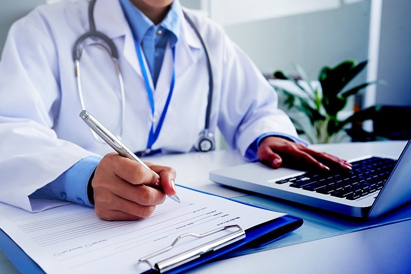 hands-unrecognizable-female-doctor-writing-form-typing-laptop-keyboard copy